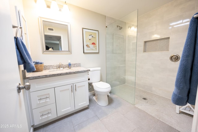 bathroom with vanity, a tile shower, tile patterned floors, and toilet