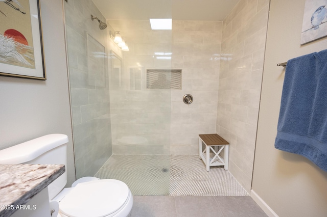 bathroom featuring tile patterned flooring, vanity, a tile shower, and toilet