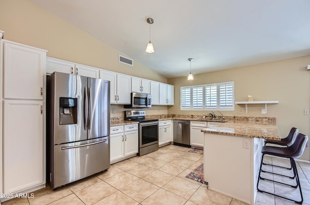 kitchen with appliances with stainless steel finishes, white cabinetry, a kitchen breakfast bar, kitchen peninsula, and pendant lighting