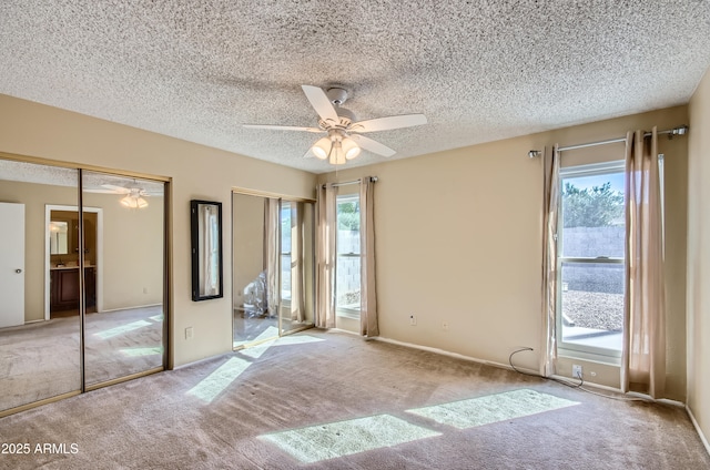 spare room with light colored carpet, a textured ceiling, and a healthy amount of sunlight