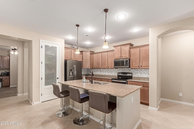 1410 W Popcorn Tree Ave, Queen Creek, AZ 85140 - kitchen with appliances with stainless steel finishes, a sink, light tile patterned floors, decorative backsplash, and a kitchen island with sink