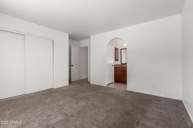 2906 W Irma Ln, Phoenix, AZ 85027 - unfurnished bedroom featuring arched walkways, light carpet, a closet, ensuite bath, and baseboards
