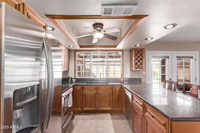 kitchen featuring sink, french doors, kitchen peninsula, a tray ceiling, and appliances with stainless steel finishes