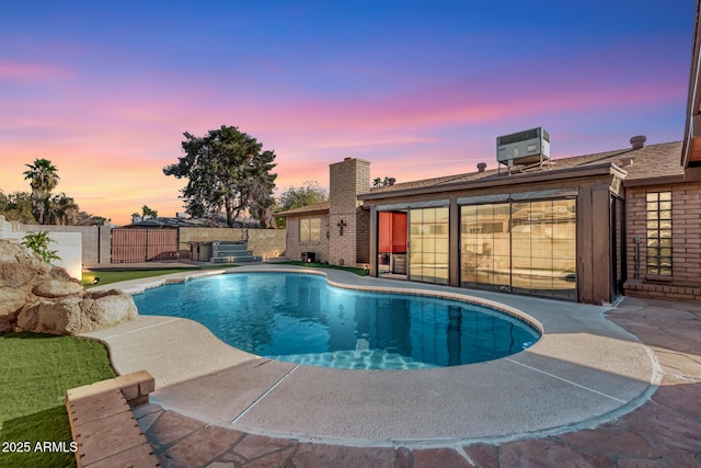 pool at dusk with a patio and central AC unit