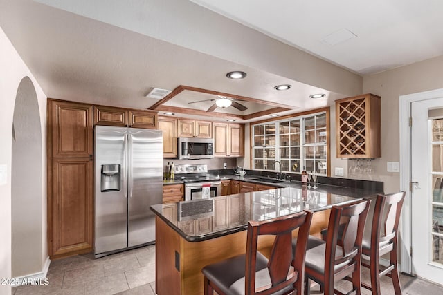 kitchen featuring kitchen peninsula, appliances with stainless steel finishes, a kitchen bar, and sink