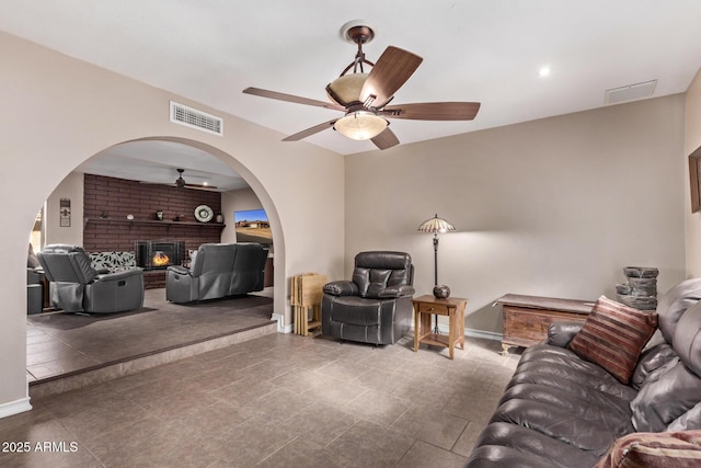 living room with a brick fireplace and ceiling fan