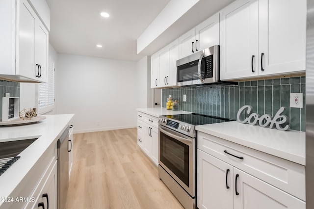 kitchen with decorative backsplash, white cabinetry, appliances with stainless steel finishes, and light hardwood / wood-style flooring