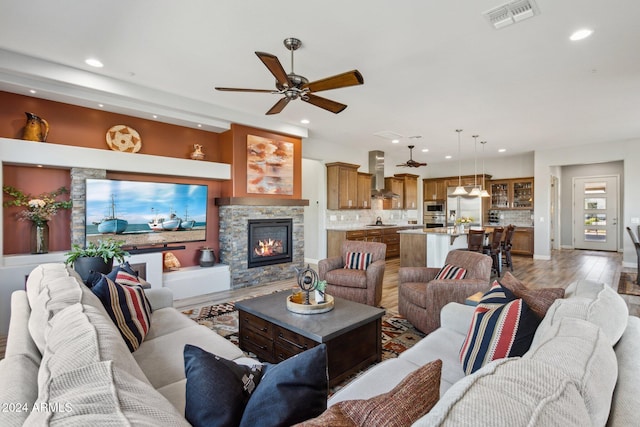 living room with ceiling fan, a fireplace, and wood-type flooring