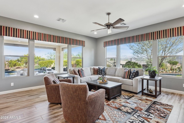 living room with light wood-type flooring, ceiling fan, and a healthy amount of sunlight