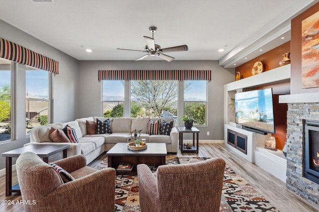 living room with a fireplace, light hardwood / wood-style flooring, and ceiling fan