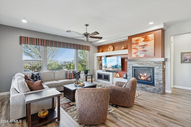 living room with a fireplace, light hardwood / wood-style flooring, and ceiling fan