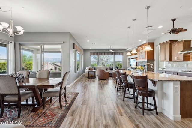 dining room featuring light wood-type flooring, ceiling fan with notable chandelier, and sink