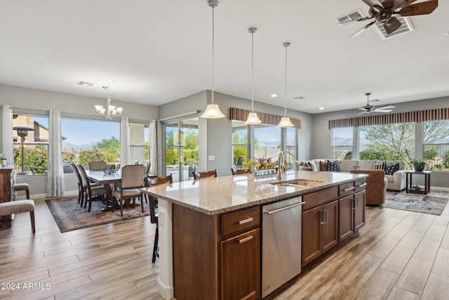 kitchen with dishwasher, ceiling fan with notable chandelier, sink, light stone countertops, and decorative light fixtures