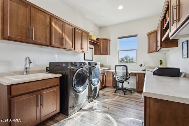 laundry area with washing machine and dryer, sink, cabinets, and light hardwood / wood-style floors