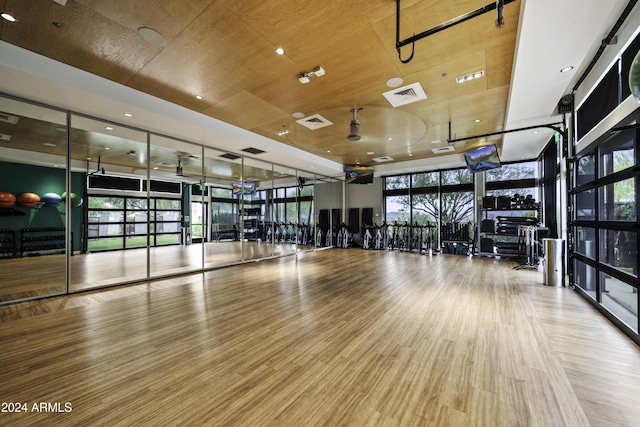 gym with hardwood / wood-style floors, a wall of windows, and wooden ceiling