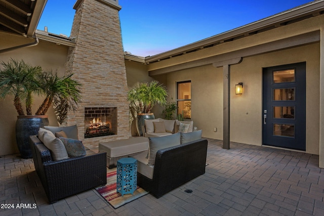 patio terrace at dusk featuring an outdoor living space with a fireplace