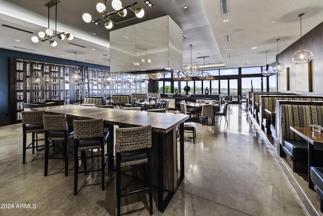 interior space featuring a large island, a wall of windows, hanging light fixtures, and concrete floors