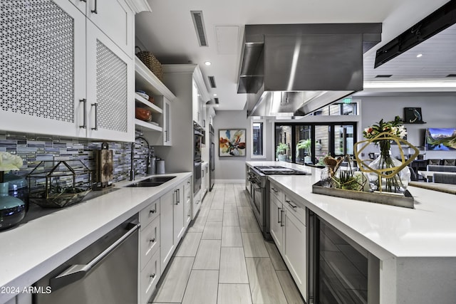 kitchen with wall chimney range hood, appliances with stainless steel finishes, white cabinetry, and sink