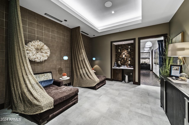 living area featuring tile walls and a tray ceiling