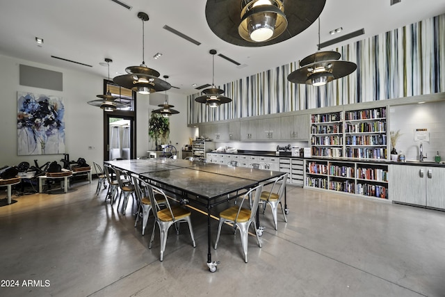 dining space with ceiling fan, sink, a high ceiling, and concrete floors