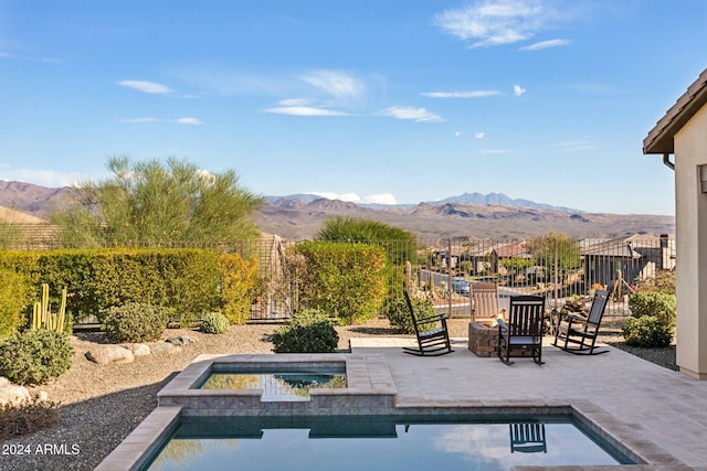 view of swimming pool with an in ground hot tub, a mountain view, a patio, and an outdoor fire pit