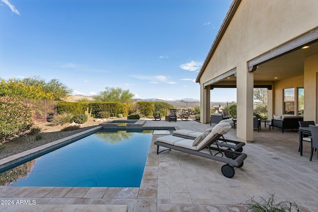 view of pool featuring a mountain view, a patio area, and an in ground hot tub