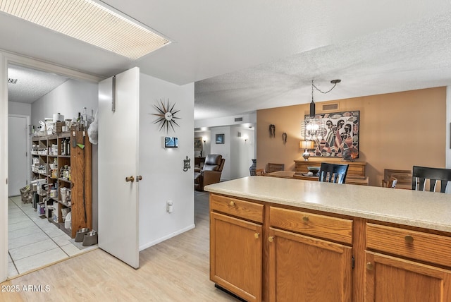 kitchen featuring a textured ceiling, light hardwood / wood-style flooring, and pendant lighting