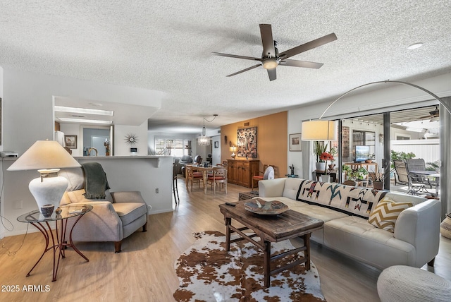 living room featuring a textured ceiling, ceiling fan, and light hardwood / wood-style floors