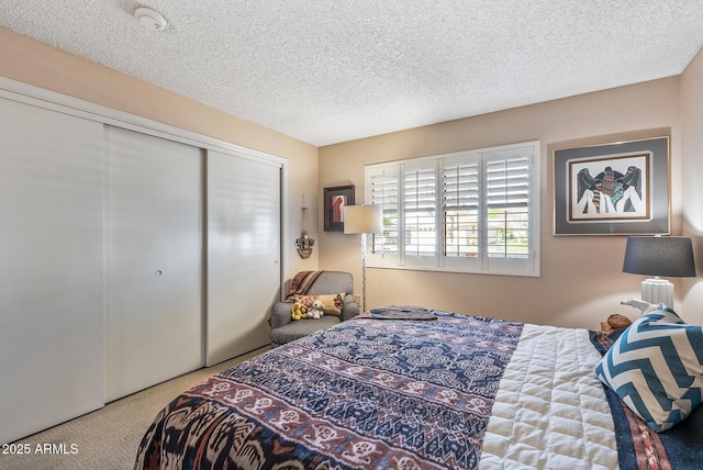 carpeted bedroom featuring a textured ceiling and a closet