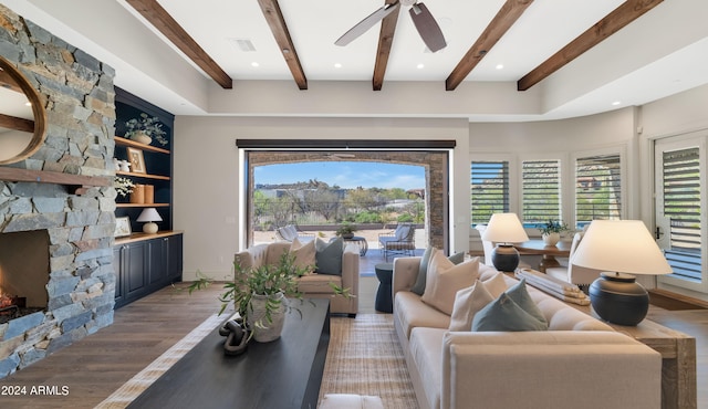 living room featuring beam ceiling, a stone fireplace, and hardwood / wood-style floors