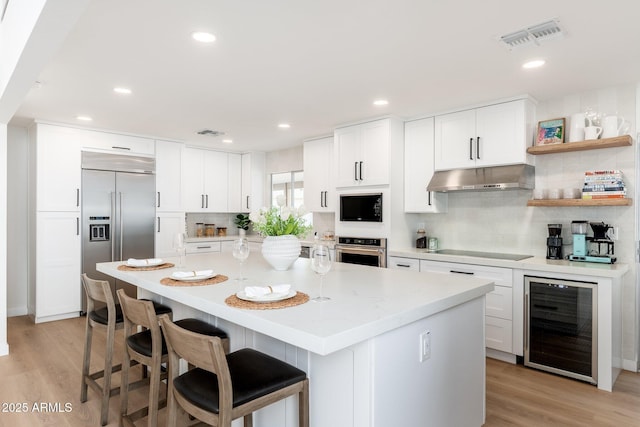 7223 N 14th St, Phoenix, AZ 85020 - kitchen featuring beverage cooler, black appliances, under cabinet range hood, decorative backsplash, and light wood-type flooring