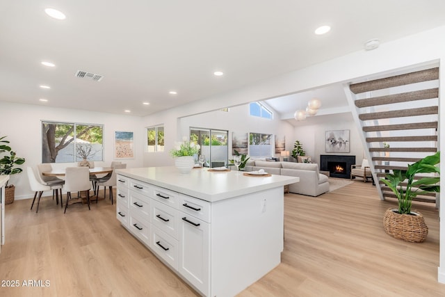 7223 N 14th St, Phoenix, AZ 85020 - kitchen with light wood-style floors, white cabinetry, light countertops, a lit fireplace, and recessed lighting