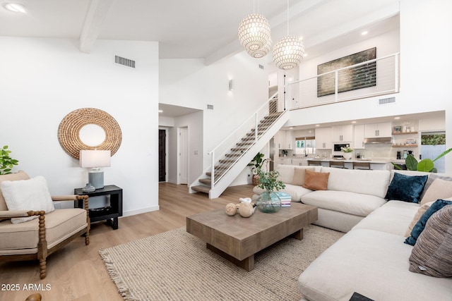 7223 N 14th St, Phoenix, AZ 85020 - living room featuring stairs, beamed ceiling, a towering ceiling, light wood-style floors, and baseboards
