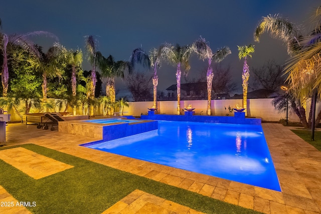 pool at twilight with an in ground hot tub and a patio