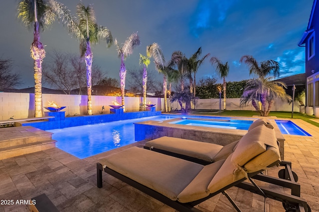 pool at dusk featuring an in ground hot tub and a patio