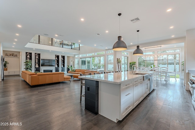 kitchen featuring dark hardwood / wood-style floors, decorative light fixtures, sink, white cabinets, and a large island