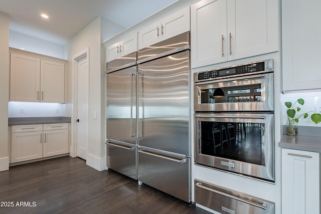 kitchen featuring stainless steel appliances, dark hardwood / wood-style floors, white cabinets, and decorative backsplash