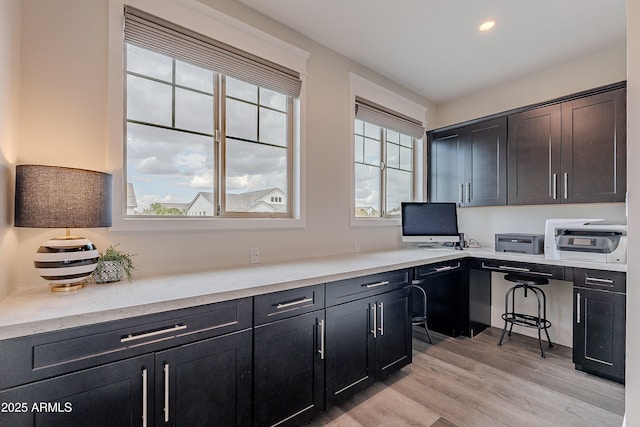 home office with built in desk and light hardwood / wood-style flooring