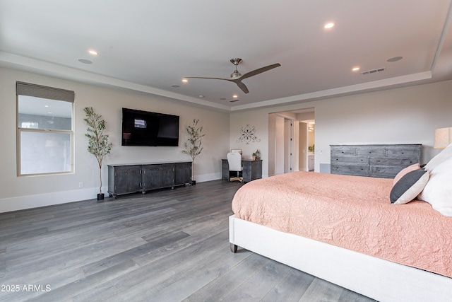 bedroom with hardwood / wood-style flooring, a raised ceiling, and ceiling fan