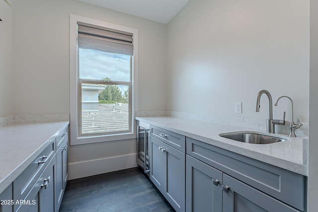 kitchen featuring sink, gray cabinetry, light stone counters, and dark wood-type flooring