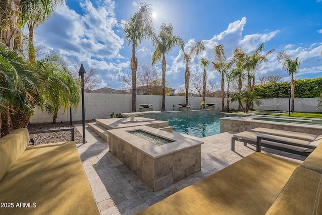 view of pool with a hot tub, pool water feature, a patio area, and an outdoor fire pit