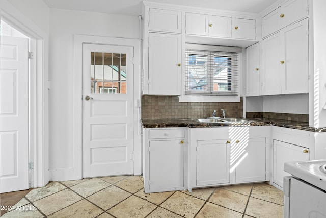 kitchen with backsplash, dark stone counters, white cabinets, sink, and range