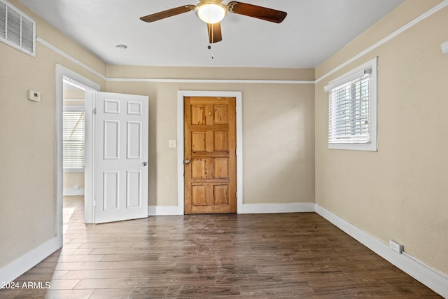 spare room featuring dark hardwood / wood-style floors, ceiling fan, and a healthy amount of sunlight