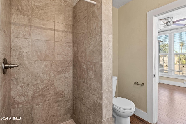 bathroom featuring hardwood / wood-style flooring, ceiling fan, toilet, and a tile shower