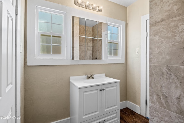 bathroom with tiled shower, vanity, and hardwood / wood-style flooring