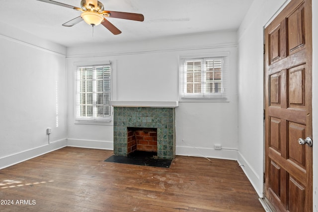 unfurnished living room with a fireplace, ceiling fan, plenty of natural light, and dark wood-type flooring