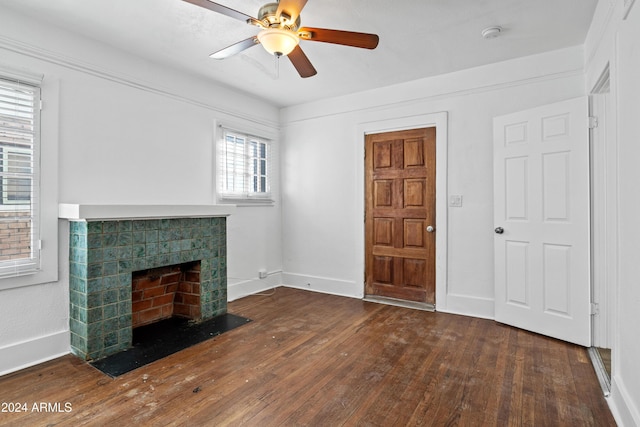 unfurnished living room featuring dark hardwood / wood-style floors, ceiling fan, and a tiled fireplace