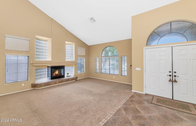 carpeted foyer with high vaulted ceiling and a tile fireplace