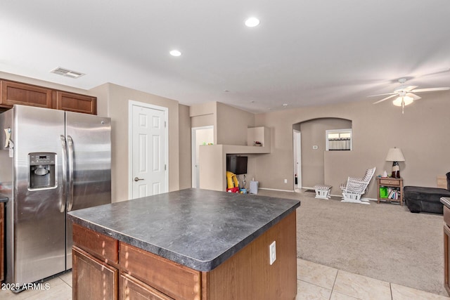 kitchen with a kitchen island, ceiling fan, stainless steel fridge with ice dispenser, and light carpet