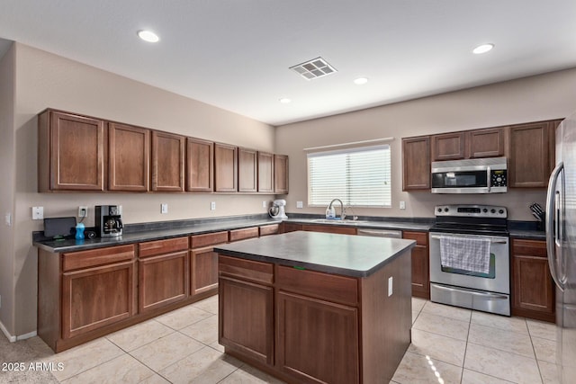 kitchen with sink, a kitchen island, light tile patterned floors, and appliances with stainless steel finishes